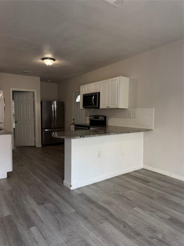 kitchen featuring kitchen peninsula, electric range, dark hardwood / wood-style floors, white cabinetry, and stainless steel refrigerator