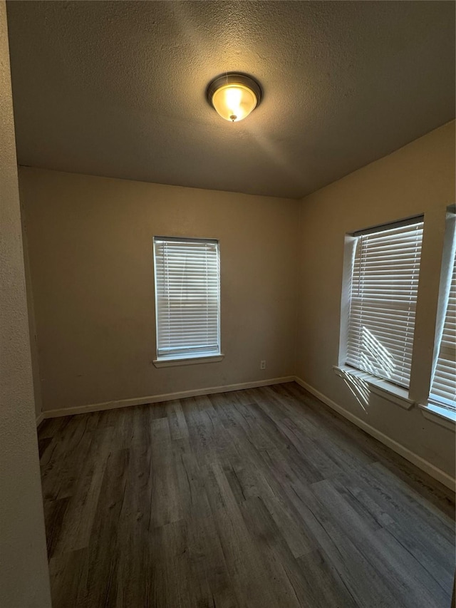 empty room with a textured ceiling and dark hardwood / wood-style flooring