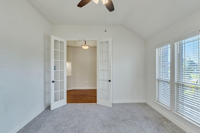 carpeted spare room with ceiling fan, lofted ceiling, and french doors