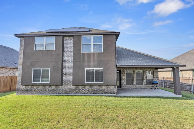 back of house with solar panels, a patio area, and a yard