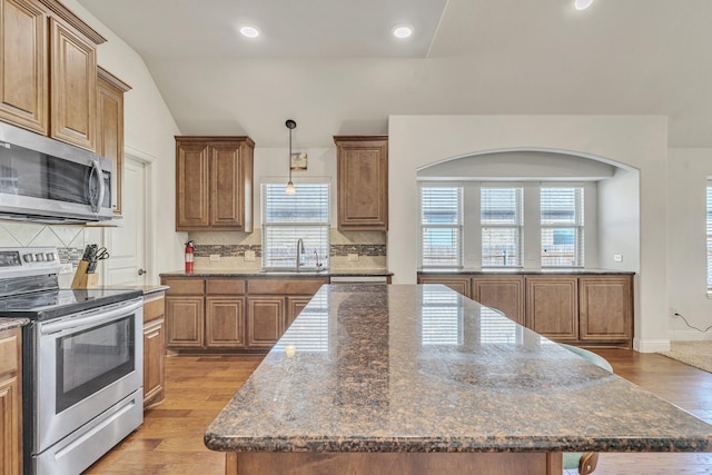 kitchen with tasteful backsplash, stainless steel appliances, a kitchen island, and plenty of natural light