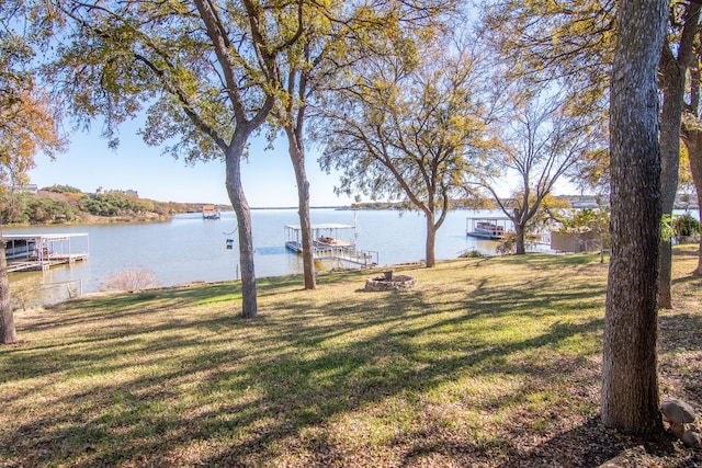 view of yard featuring a water view, a dock, and an outdoor fire pit