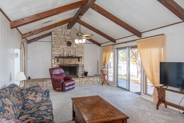 carpeted living room with vaulted ceiling with beams, ceiling fan, and a stone fireplace