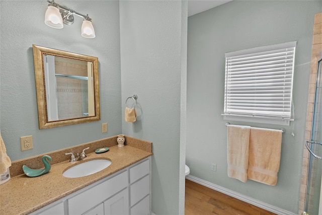 bathroom featuring hardwood / wood-style flooring, vanity, an enclosed shower, and toilet