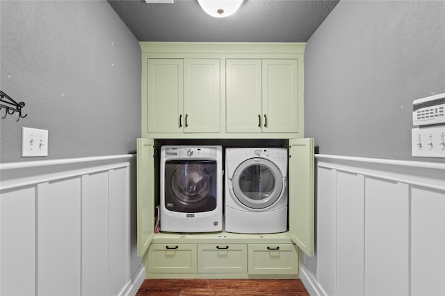 washroom featuring hardwood / wood-style flooring, a textured ceiling, cabinets, and washing machine and clothes dryer