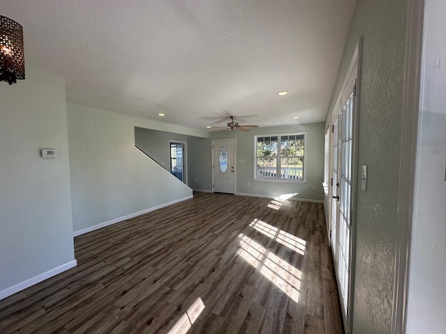 unfurnished living room featuring a textured ceiling, dark hardwood / wood-style flooring, and ceiling fan