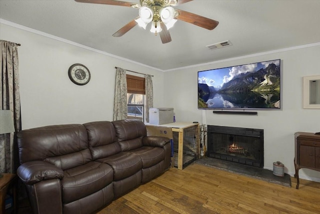 living room featuring hardwood / wood-style flooring, crown molding, and ceiling fan