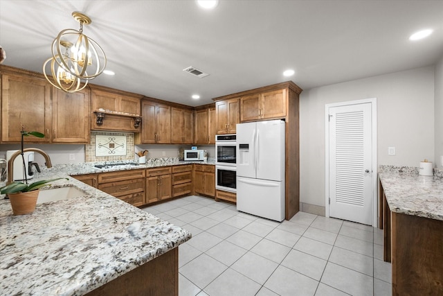 kitchen with pendant lighting, an inviting chandelier, sink, light tile patterned floors, and stainless steel appliances