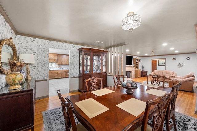 dining space with light wood finished floors, an inviting chandelier, recessed lighting, crown molding, and a fireplace