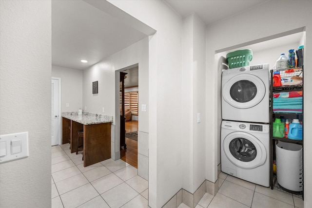 laundry area featuring light tile patterned flooring and stacked washer and dryer