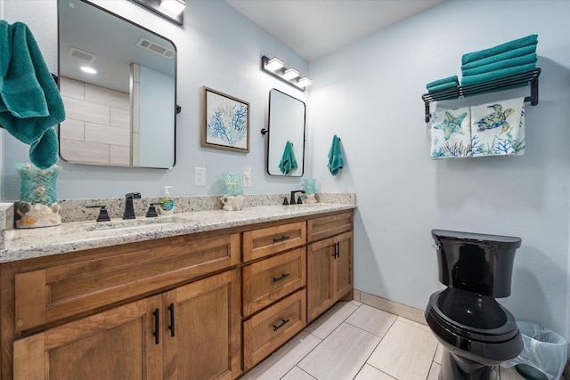 bathroom featuring tile patterned flooring, double vanity, visible vents, a sink, and baseboards