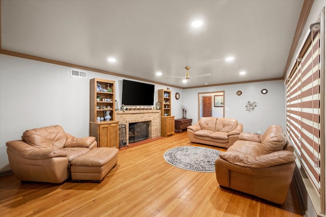 living room featuring a brick fireplace, ceiling fan, ornamental molding, and hardwood / wood-style flooring