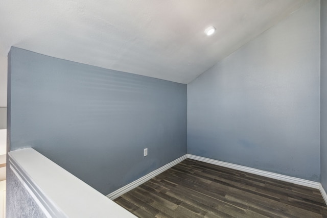 additional living space featuring dark wood-type flooring and vaulted ceiling