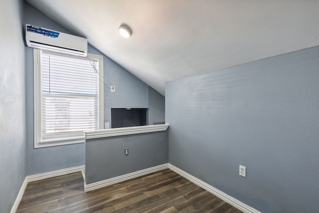 bonus room featuring vaulted ceiling, a wall mounted AC, and dark wood-type flooring