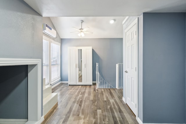 interior space featuring hardwood / wood-style flooring, ceiling fan, a wall mounted air conditioner, and lofted ceiling