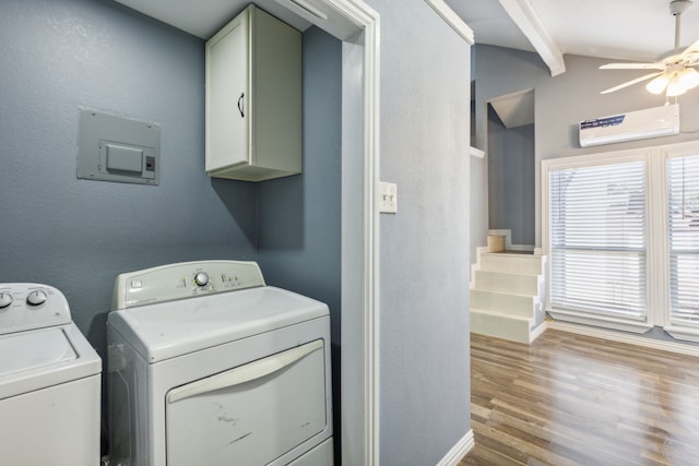 clothes washing area featuring cabinets, a wall mounted air conditioner, ceiling fan, washer and dryer, and light hardwood / wood-style floors