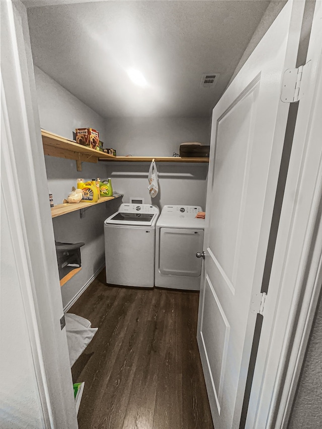 laundry area featuring dark wood-type flooring, washer and clothes dryer, and a textured ceiling