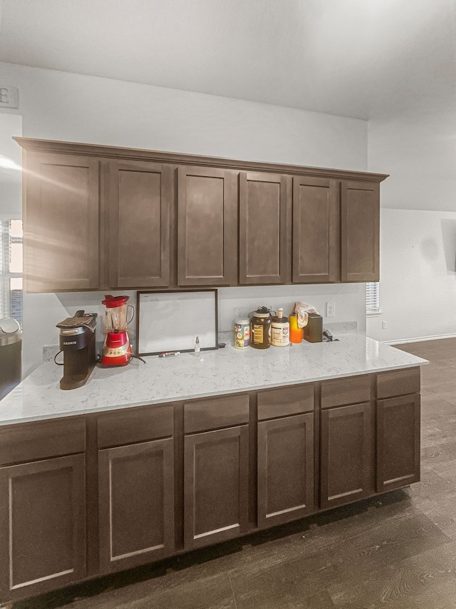 kitchen featuring light stone counters, dark hardwood / wood-style floors, and dark brown cabinets