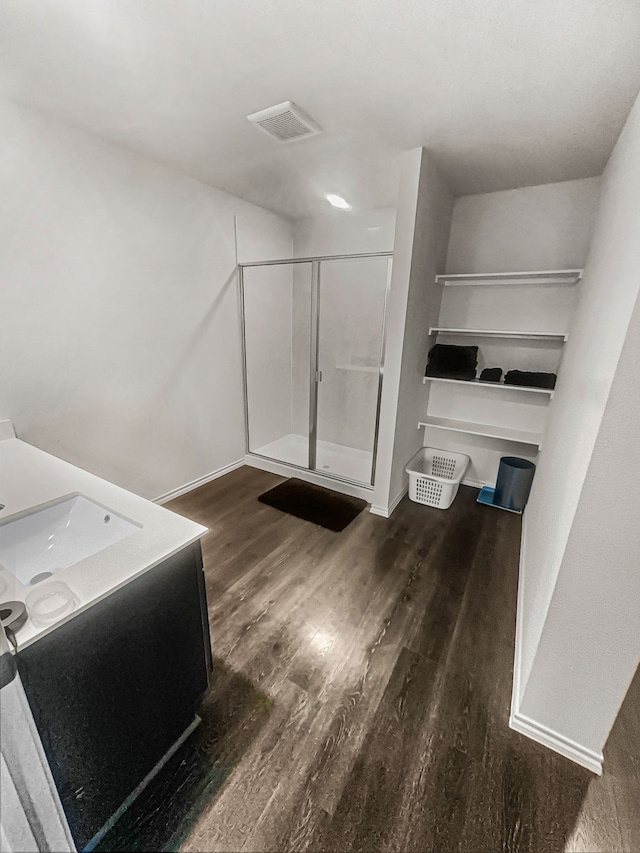 bathroom featuring wood-type flooring, a shower with shower door, and vanity