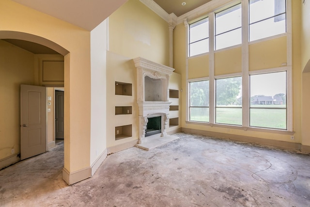 unfurnished living room with built in shelves and a high ceiling