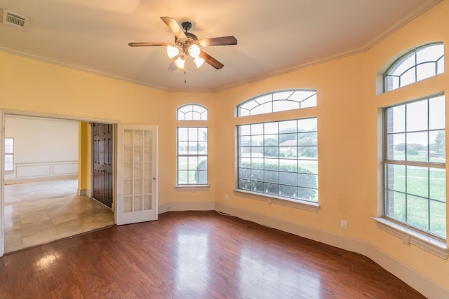 empty room featuring crown molding, plenty of natural light, ceiling fan, and hardwood / wood-style flooring