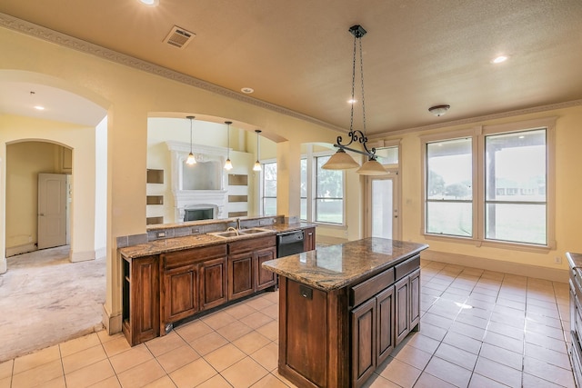 kitchen featuring sink, hanging light fixtures, stone countertops, a kitchen island, and light colored carpet