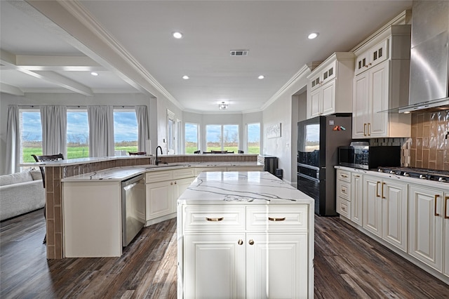 kitchen featuring white cabinetry, a center island, wall chimney exhaust hood, and appliances with stainless steel finishes