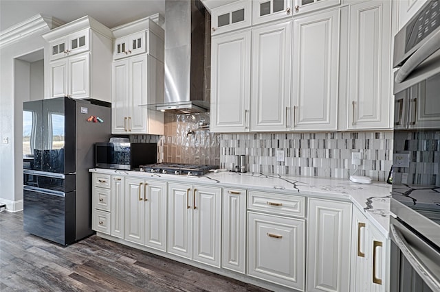 kitchen featuring white cabinetry, light stone counters, stainless steel appliances, dark wood-type flooring, and wall chimney exhaust hood