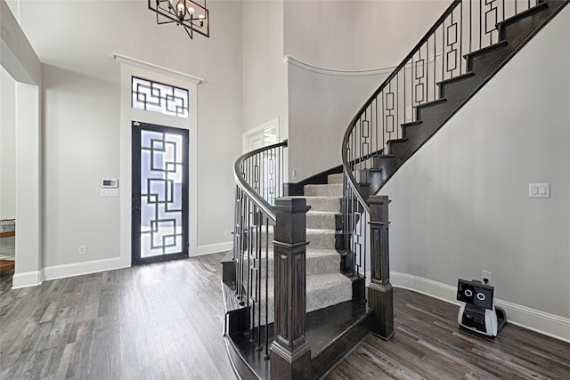 entryway with an inviting chandelier, dark hardwood / wood-style floors, and a high ceiling