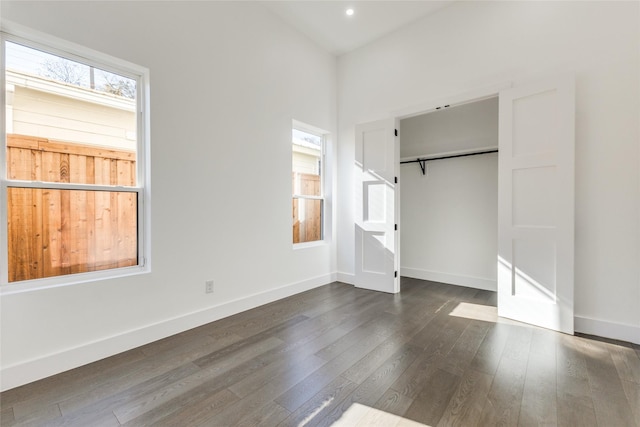 unfurnished bedroom featuring a closet, dark wood-type flooring, and a barn door