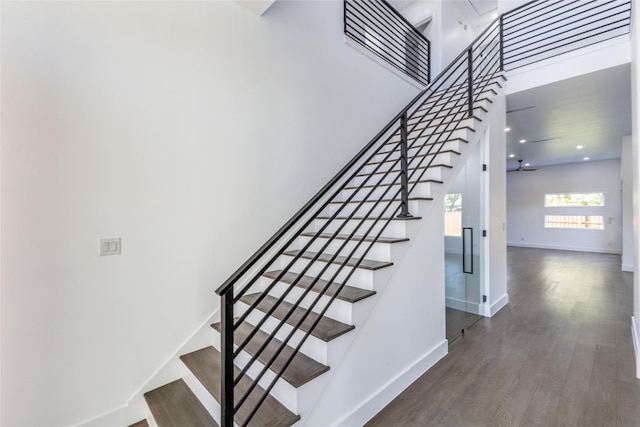 staircase featuring hardwood / wood-style floors and a towering ceiling