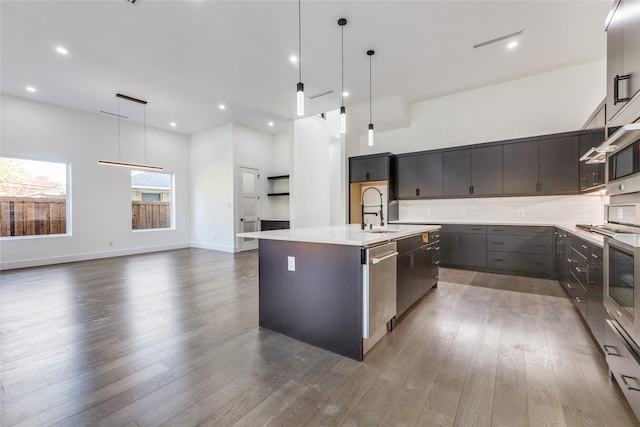 kitchen featuring a kitchen island with sink, sink, pendant lighting, and dark hardwood / wood-style floors