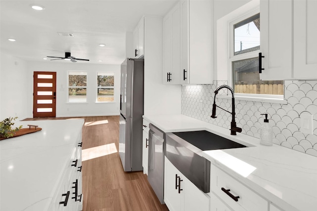 kitchen with decorative backsplash, light stone countertops, white cabinets, and stainless steel appliances