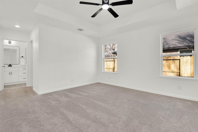 spare room featuring ceiling fan, light colored carpet, and a tray ceiling