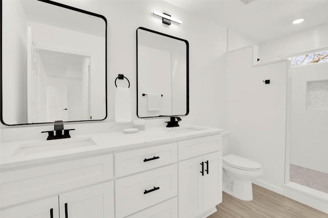 bathroom with hardwood / wood-style floors, toilet, vanity, and walk in shower