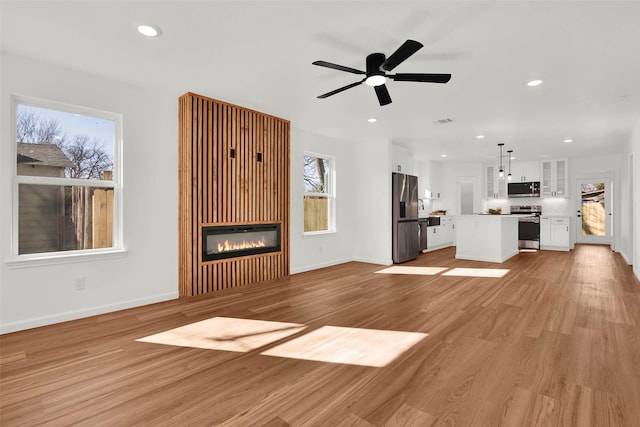 unfurnished living room featuring light wood-type flooring and ceiling fan