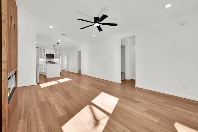 unfurnished living room featuring ceiling fan and light hardwood / wood-style flooring