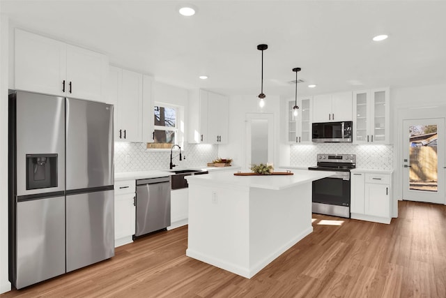 kitchen with a kitchen island, white cabinetry, decorative light fixtures, and appliances with stainless steel finishes