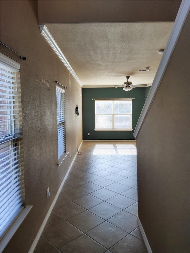 hallway with tile patterned floors, crown molding, and a textured ceiling