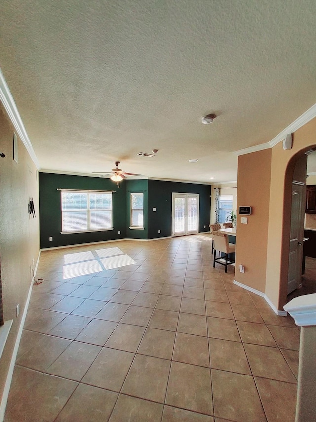 unfurnished room featuring a textured ceiling, ceiling fan, crown molding, and light tile patterned flooring