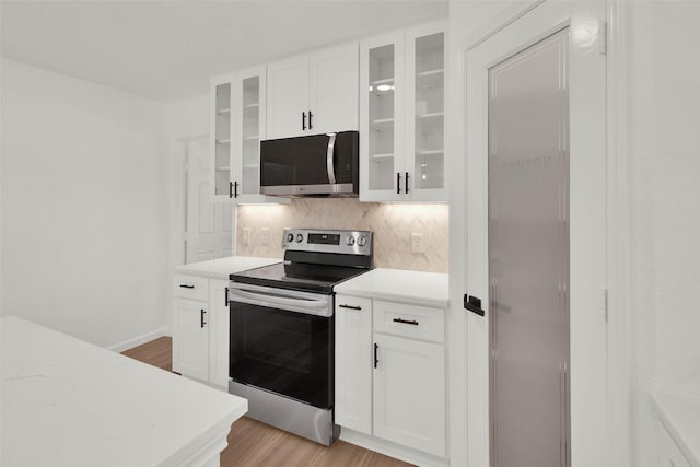 kitchen with light hardwood / wood-style floors, white cabinets, stainless steel appliances, and tasteful backsplash