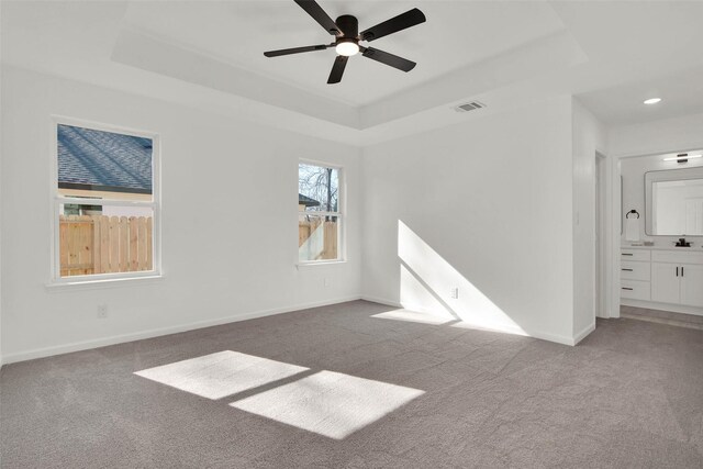 carpeted spare room with ceiling fan and a raised ceiling