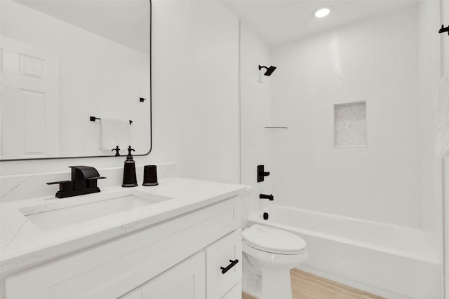 full bathroom with wood-type flooring, tiled shower / bath combo, vanity, and toilet