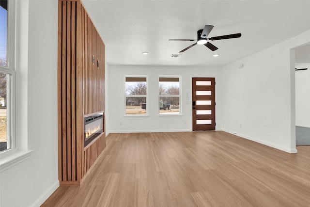 unfurnished living room with light wood-type flooring and ceiling fan