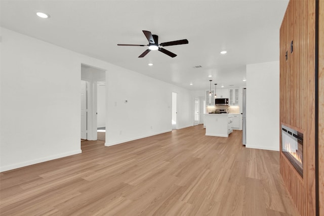 unfurnished living room with light wood-type flooring and ceiling fan