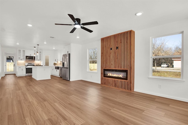 unfurnished living room featuring ceiling fan, plenty of natural light, and light hardwood / wood-style flooring