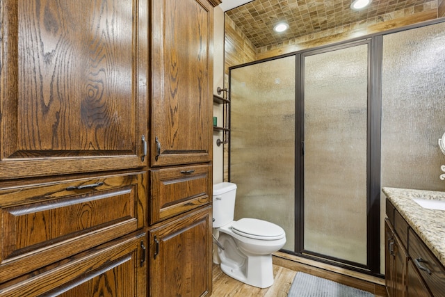 bathroom with vanity, hardwood / wood-style floors, an enclosed shower, and toilet