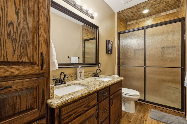 bathroom featuring vanity, hardwood / wood-style floors, a shower with shower door, and toilet