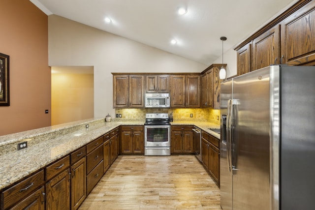 kitchen featuring vaulted ceiling, hanging light fixtures, kitchen peninsula, stainless steel appliances, and light stone countertops