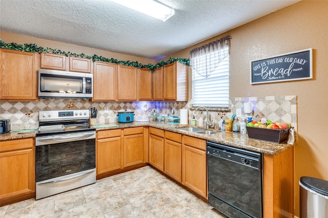 kitchen with stainless steel appliances, light stone counters, a sink, and tasteful backsplash